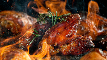 Tasty chicken legs on cast iron grate with fire flames. Freeze motion barbecue concept.