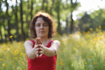 Field of flowers with detail of the hands in yoga practice in the new normality after Covid 19..