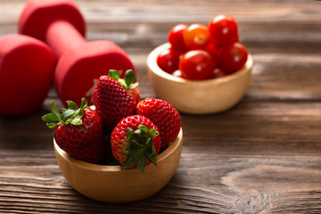 Healthy foods  Concept ,  strawberry  with dumbbells on wood background