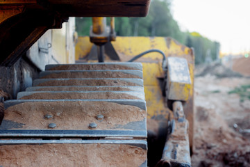bulldozer stands on the sand near the forest. close-up of a metal track of a bulldozer. laying a new road along the forest