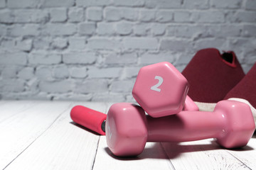 close up of dumbbell, shoe on pink background 