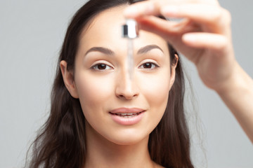 Fototapeta premium Young beautiful woman with pipette with clean perfect skin closeup