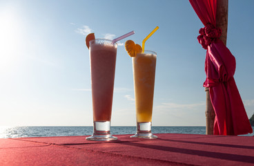 Two tropical fresh icy cocktails at a beach table