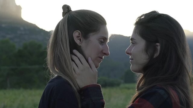 Lesbian girls couple hugging and kissing under the sunset. LGBT