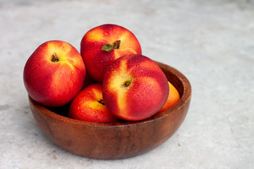 Fresh ripe nectarines in a wooden bowl