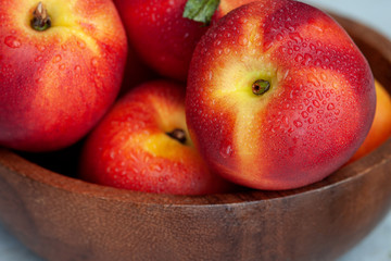 Fresh ripe nectarines in a wooden bowl