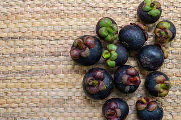 Mangosteens placed on traditional wickerwork texture made form dried stalk water hyacinth or Eichhornia crassipes. Top view with copy space. Queen of fruit in thailand.