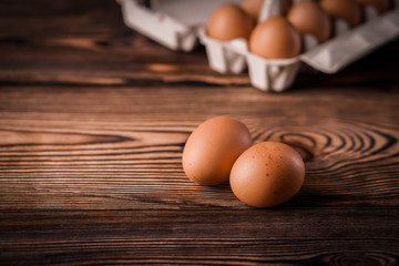 Detail close-up of chicken eggs on the old brown wooden background.