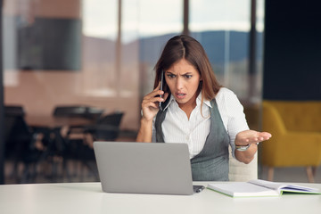 Bored young woman dressed in shirt sitting at her workplace