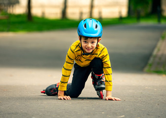 A boy tries to get up from the ground after falling with the roller skates