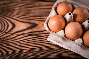 Detail close-up of chicken eggs on the old brown wooden background.