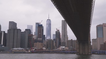 New York, USA, 2019. View on downtown from under Brooklyn Bridge. One World Trade Center on overcast weather