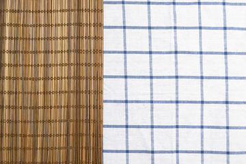 Brown bamboo mat on table cloth with blue grid pattern. Creative layout background.