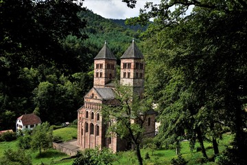 Fototapeta na wymiar Murbach Abbey hidden behind trees with town hall of Murbach