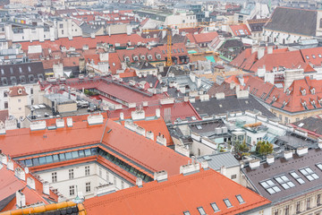 Fototapeta na wymiar Cityscape with red tiles rooftops of the old town of Vienna in a heavy snowy day. View at the tower of St. Stephen's Cathedral in Vienna, Austria.
