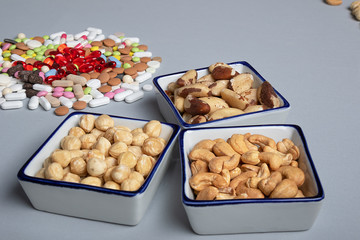 Healthy lifestyle concept. Pills and types of roasted nuts on gray background. Immunity and healthy fats for beauty