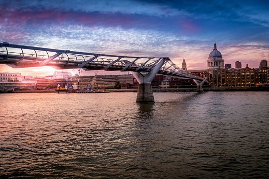 Millennium Bridge Over River Thames By St Pauls Cathedral Against Sky At Sunset