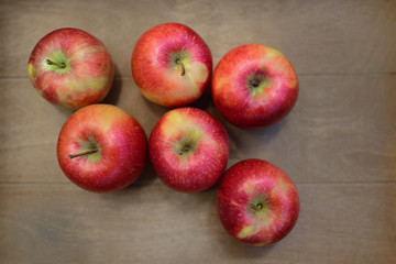 individual red apples lie in a wooden box and are photographed from above