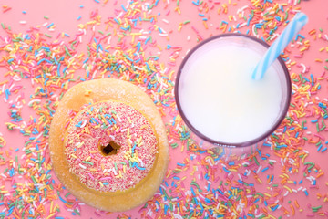 Top view of donuts and milk on pink.