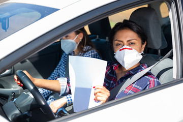 Hispanic woman in medical mask with blank paper driving car