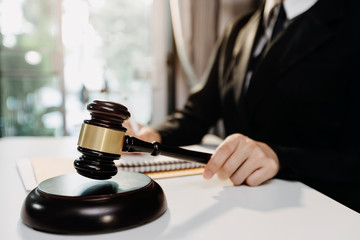 Justice and law concept.Male judge in a courtroom with the gavel, working with, computer and docking keyboard, eyeglasses, on table in morning ligh
