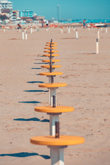 A row of yellow beach tables set at safety distance. Preparing the beach for the season after COVID emergency lockfown. Setting tables at safety distance. Vintage feel.