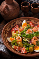 Hospitable Georgian cuisine. Salad with salmon, egg, tomatoes and arugula
