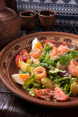 Hospitable Georgian cuisine. Salad with salmon, egg, tomatoes and arugula
