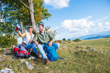 Young couple drinking water while resting on the rock during the travel in the mountains