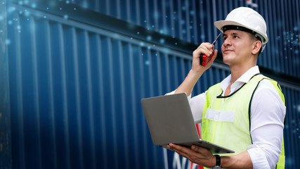 Engineer or foreman use walkie-talkie and laptop. In order to move container and shipping. Safety...