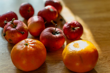 Bright juicy fruits, natural and natural fruits with damage. Red apples and tangerines on a modern brown light table