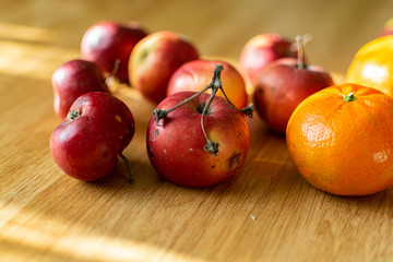 Bright juicy fruits, natural and natural fruits with damage. Red apples and tangerines on a modern brown light table