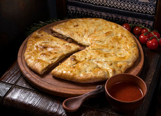 Hospitable Georgian cuisine. Khachapuri with meat on a wooden background