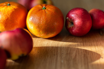 Bright juicy fruits, natural and natural fruits with damage. Red apples and tangerines on a modern brown light table