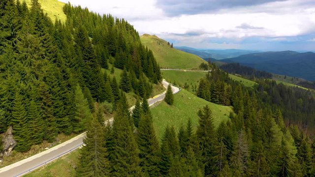 Motorcyclist driving his motorbike on the mountain forest road in the country side. A young man riding a motorbike on a countryside road. Motorbike driving along the wild mountain forest road. Aerials