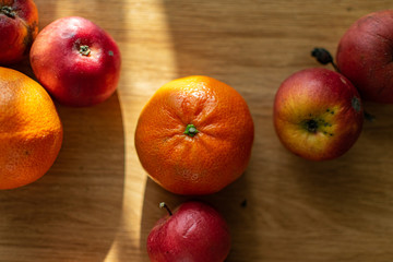 Bright juicy fruits, natural and natural fruits with damage. Red apples and tangerines on a modern brown light table