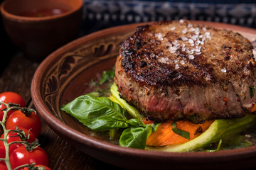 grilled steak with greens in a round ethnic plate. Georgian cuisine