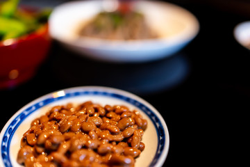 Macro closeup of Asian Japanese natto fermented soy dish meal sticky slimy texture in plate bowl with black background kaiseki meal