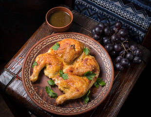 Grilled chicken with greens in a round ethnic plate. Georgian cuisine