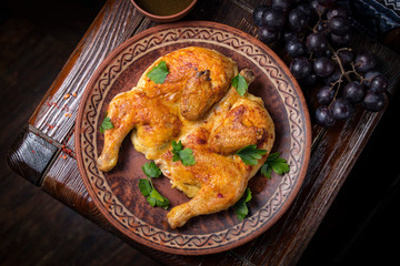 Grilled chicken with greens in a round ethnic plate. Georgian cuisine