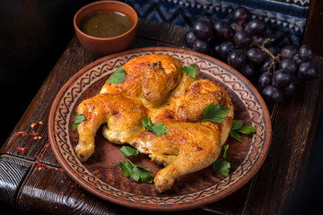 Grilled chicken with greens in a round ethnic plate. Georgian cuisine