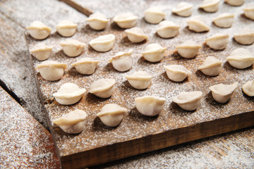 Semi-finished pelmeni dumplings on wooden board