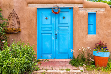Fototapeta premium Tradycyjna kolorowa architektura Nowego Meksyku z niebiesko-turkusowymi kolorami adobe i dekoracjami w ogrodzie przy wejściu