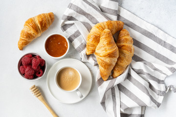 Freshly baked croissants with berries, homemade jam and aromatic coffee for Breakfast on a grey table, top view. Concept of healthy and delicious food.