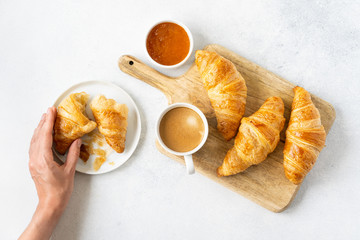 Freshly baked croissants with berries, homemade jam and aromatic coffee for Breakfast on a grey table, top view. Concept of healthy and delicious food.