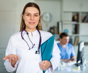 Female doctor in lab coat holding clipboard with medical records