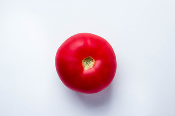 One red tomato on a white background. Photo above