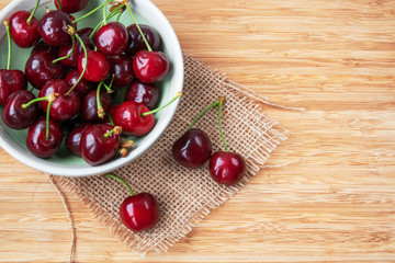 Fototapeta na wymiar Cherries in a bowl on wooden background