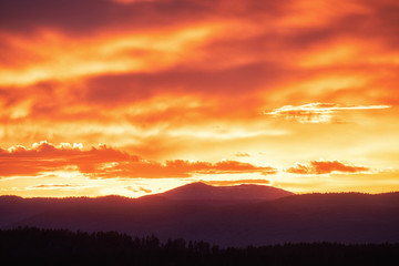 Fototapeta premium Sun setting over hills. Red clouds