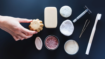 A hand picks up a solid soap between various ecological objects
